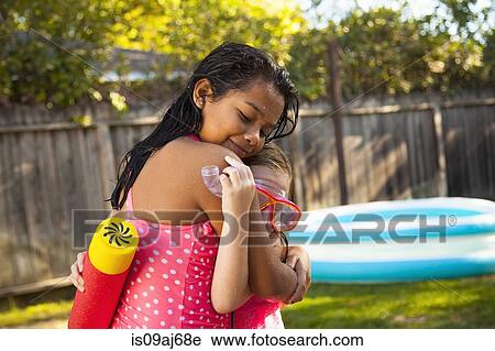 Stock Image - Two girls hugging in garden. Fotosearch