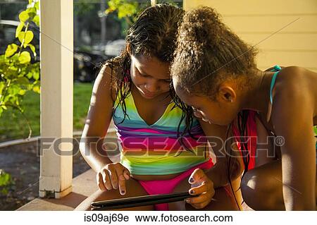 Two girls in porch looking at digital tablet View Large Photo Image Stock Image - Two girls in porch looking at digital tablet. Fotosearch