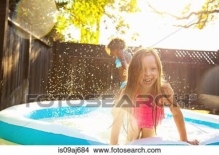 Picture - Two girls playing in garden paddling pool. Fotosearch