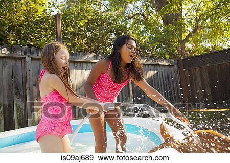 Two girls splashing dog with hosepipe in garden paddling pool View Large Photo Image Stock Photo - Two girls splashing dog with hosepipe in garden paddling pool. Fotosearch