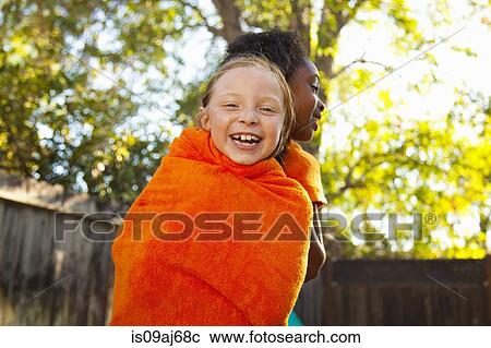 Two girls wrapped in orange towel in garden View Large Photo Image Stock Image - Two girls wrapped in orange towel in garden. Fotosearch
