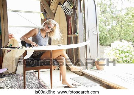 Young female surfer sitting in shed waxing her surfboard View Large Photo Image Stock Photo - Young female surfer sitting in shed waxing her surfboard. Fotosearch
