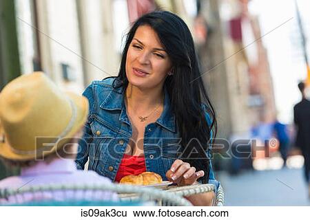 Stock Photograph - Young mother and son having cake at sidewalk cafe. Fotosearch