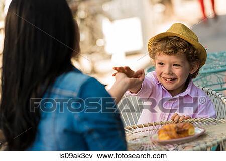 Young mother and son touching hands over table at sidewalk cafe View Large Photo Image Stock Photo - Young mother and son touching hands over table at sidewalk cafe. Fotosearch