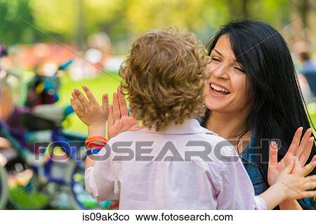 Young mother and son with hands together in park View Large Photo Image Picture - Young mother and son with hands together in park. Fotosearch