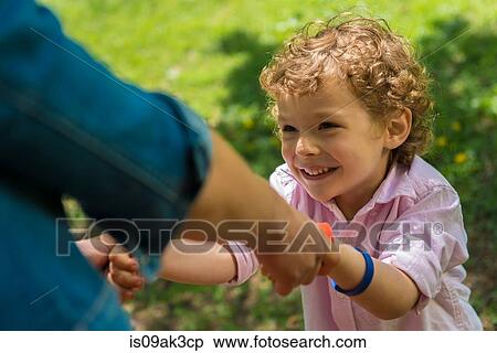 Stock Photography - Young mother holding son's hands in park. Fotosearch