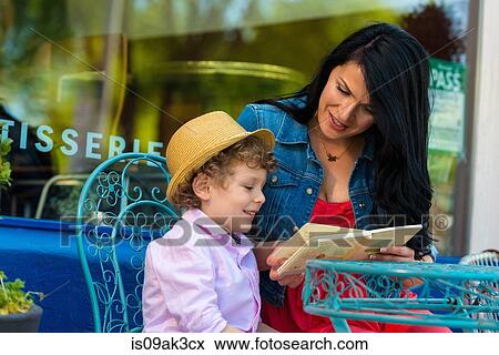 Young mother reading story book with son at sidewalk cafe View Large Photo Image Stock Photo - Young mother reading story book with son at sidewalk cafe. Fotosearch