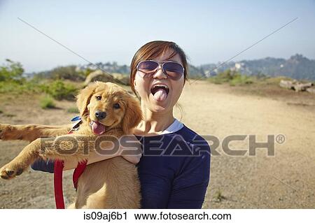 Young woman holding labrador puppy, tongues out View Large Photo Image Stock Image - Young woman holding labrador puppy, tongues out. Fotosearch