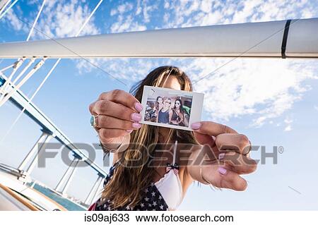 Young woman holding photo in front of face View Large Photo Image Stock Image - Young woman holding photo in front of face. Fotosearch