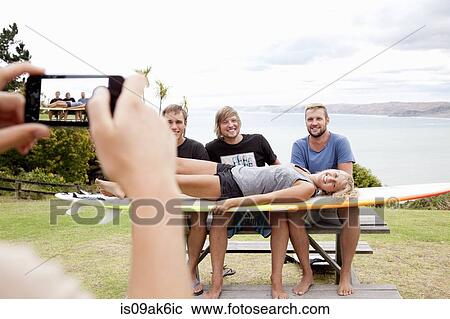 Young woman photographing surfer friends with smartphone View Large Photo Image Stock Image - Young woman photographing surfer friends with smartphone. Fotosearch