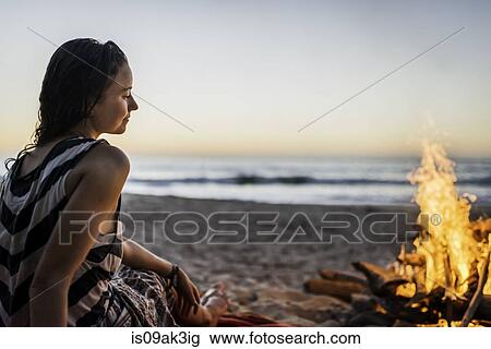 Young woman sitting by bonfire on beach View Large Photo Image Stock Image - Young woman sitting by bonfire on beach. Fotosearch