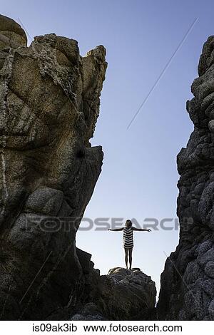 Young woman standing on rocks on beach, arms outstretched View Large Photo Image Stock Image - Young woman standing on rocks on beach, arms outstretched. Fotosearch