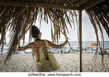 Young woman standing under cabana looking out to sea View Large Photo Image Stock Photo - Young woman standing under cabana looking out to sea. Fotosearch