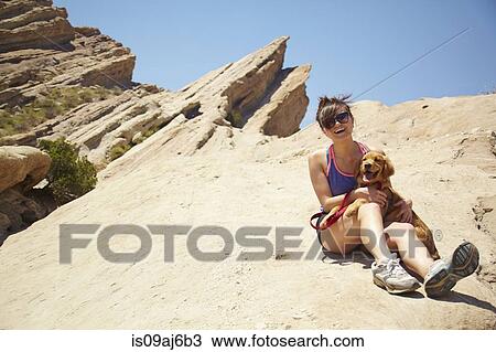 Stock Image - Young woman with labrador puppy sitting on lap. Fotosearch