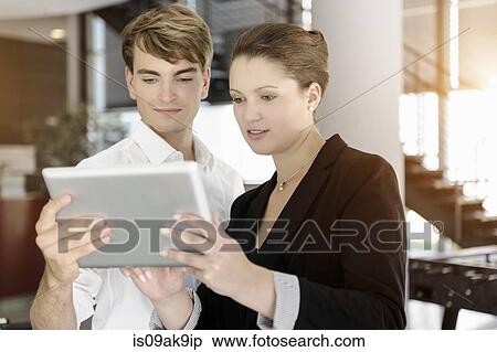 Stock Photography - Businesswoman and businessman using digital tablet for discussion. Fotosearch