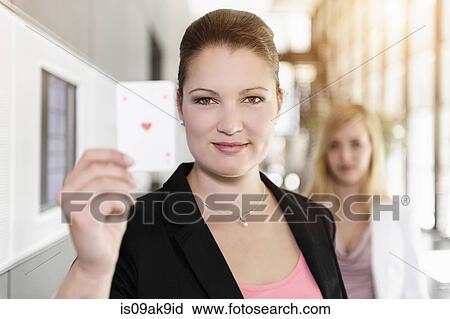 Stock Image - Businesswoman holding up Ace of Hearts card. Fotosearch