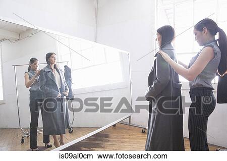Picture - Businesswoman trying on coat. Fotosearch