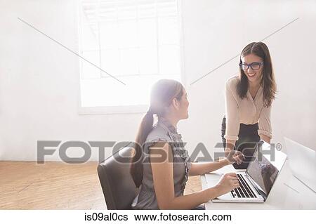 Stock Photograph - Businesswoman using laptop with manager smiling. Fotosearch