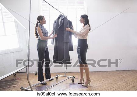 Businesswomen choosing smart clothes from clothes rail View Large Photo Image Stock Image - Businesswomen choosing smart clothes from clothes rail. Fotosearch