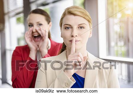 Stock Photo - Businesswomen hiding and letting out secret. Fotosearch