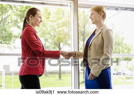 Stock Image - Businesswomen shaking hands. Fotosearch