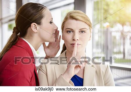 Stock Image - Businesswomen sharing secret. Fotosearch