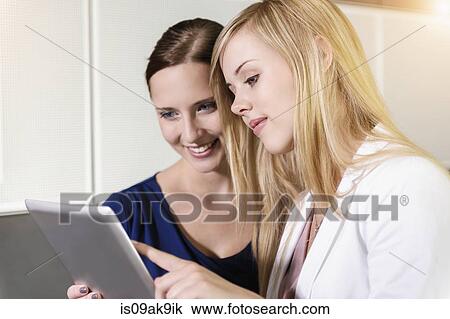 Stock Image - Businesswomen using digital tablet for discussion. Fotosearch
