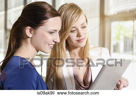 Stock Image - Businesswomen using digital tablet for discussion. Fotosearch