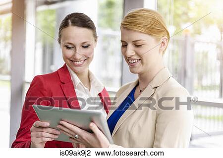 Stock Image - Businesswomen using digital tablet for discussion. Fotosearch