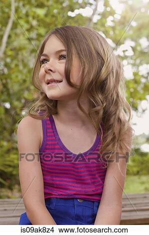 Picture - Candid portrait of girl sitting in garden looking away. Fotosearch