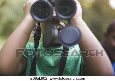 Stock Image - Close up of girl looking through binoculars in forest eco camp. Fotosearch