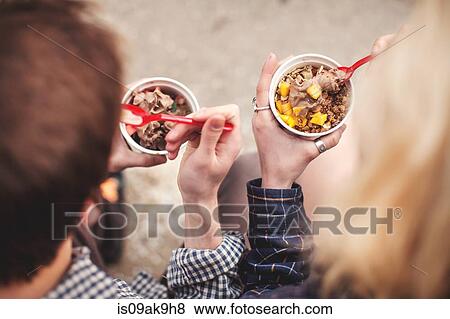 Couple eating tubs of frozen yoghurt treat View Large Photo Image Stock Photo - Couple eating tubs of frozen yoghurt treat. Fotosearch