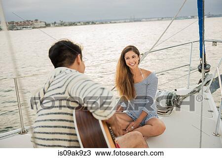 Couple on sailing boat, man playing guitar View Large Photo Image Stock Image - Couple on sailing boat, man playing guitar. Fotosearch