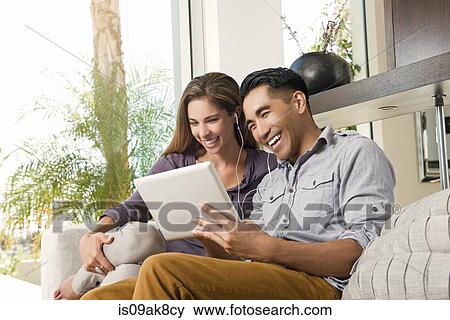 Stock Photo - Couple on sitting room sofa looking at digital tablet. Fotosearch