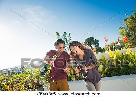 Couple opening champagne in penthouse rooftop garden, La Jolla, California, USA View Large Photo Image Stock Photography - Couple opening champagne in penthouse rooftop garden, La Jolla, California, USA. Fotosearch