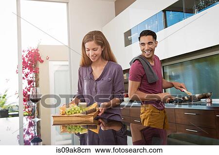 Couple preparing cheeseboard and cooking in kitchen View Large Photo Image Picture - Couple preparing cheeseboard and cooking in kitchen. Fotosearch