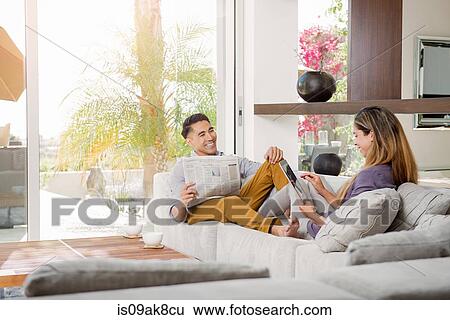 Couple reading newspaper and looking at digital tablet on sitting room sofa View Large Photo Image Stock Photograph - Couple reading newspaper and looking at digital tablet on sitting room sofa. Fotosearch