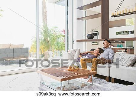 Couple relaxing together on sitting room sofa View Large Photo Image Stock Photography - Couple relaxing together on sitting room sofa. Fotosearch