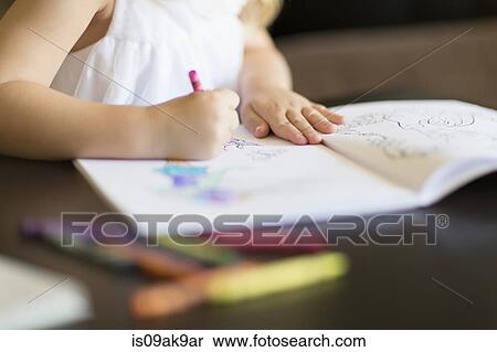 Stock Photography - Cropped shot of girl coloring in book with crayons. Fotosearch