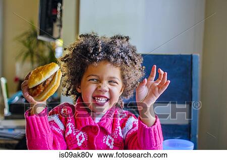 Cute girl laughing and holding up hamburger in kitchen View Large Photo Image Stock Photo - Cute girl laughing and holding up hamburger in kitchen. Fotosearch