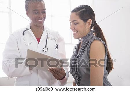Stock Image - Female doctor showing patient digital tablet. Fotosearch