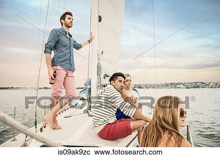 Stock Image - Friends on sailing boat looking at view. Fotosearch