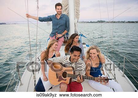 Friends on sailing boat, man playing guitar View Large Photo Image Stock Photo - Friends on sailing boat, man playing guitar. Fotosearch