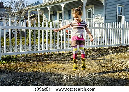 Girl jumping mid air into garden puddle View Large Photo Image Stock Image - Girl jumping mid air into garden puddle. Fotosearch