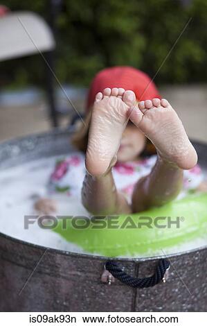 Girl sitting in bubble bath in garden with feet sticking out View Large Photo Image Picture - Girl sitting in bubble bath in garden with feet sticking out. Fotosearch