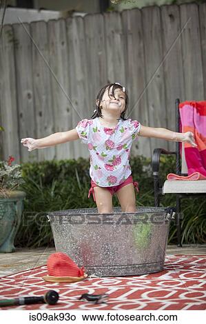 Girl standing in bathtub in garden with arms outstretched View Large Photo Image Picture - Girl standing in bathtub in garden with arms outstretched. Fotosearch
