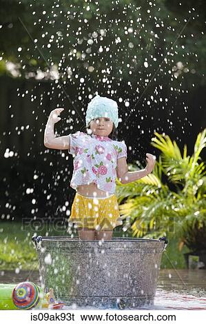 Stock Photograph - Girl standing in bubble bath in garden splashing soap bubbles. Fotosearch