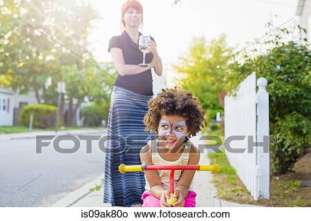 Girl with painted face crouching on scooter on suburban street View Large Photo Image Picture - Girl with painted face crouching on scooter on suburban street. Fotosearch