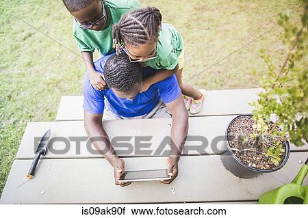 High angle view of father looking at digital tablet with daughter and son at eco camp View Large Photo Image Stock Image - High angle view of father looking at digital tablet with daughter and son at eco camp. Fotosearch