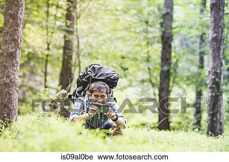 Stock Image - Hiker taking photo on camera phone in forest. Fotosearch